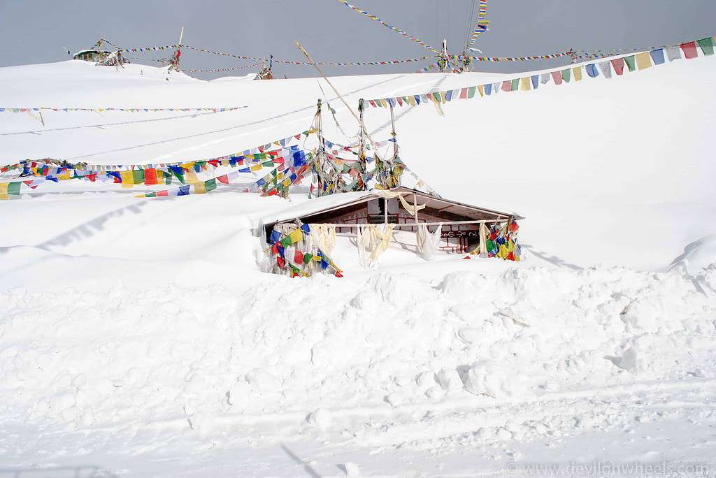 Snowbound shrine covered in prayer flags on a high mountain pass in Ladakh