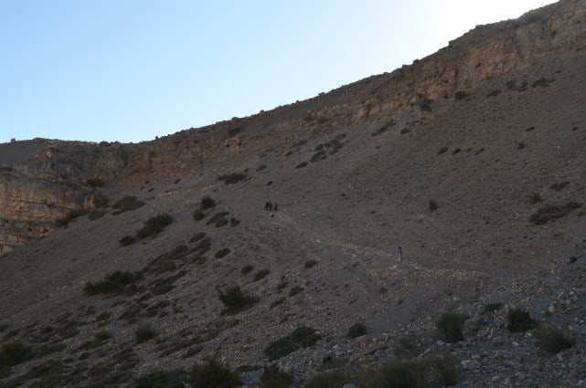 Trekkers climbing the barren slope above Mane village on the trail to Sopona Lake in Spiti