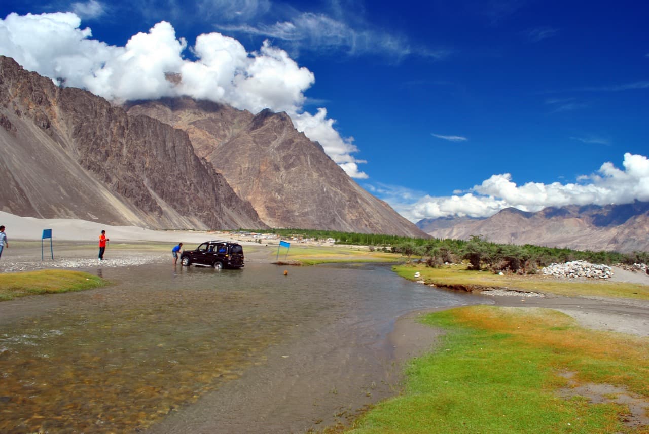 SUV crossing a shallow stream at Hunder in Nubra Valley on a Leh Ladakh road trip by car