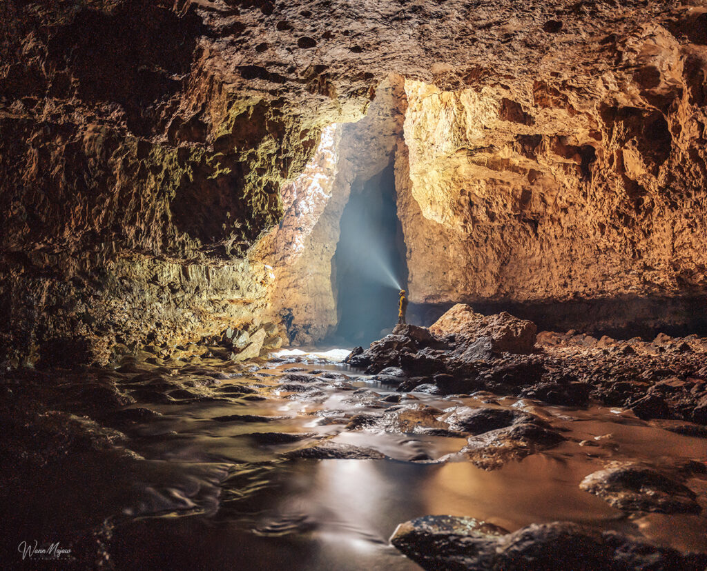 Caver with headlamp inside the stream passage of Mawmluh Cave Sohra