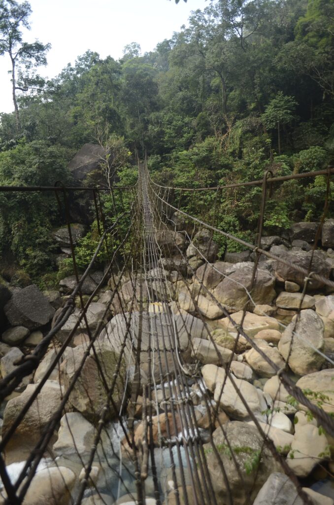 Steel wire suspension bridge over a boulder-filled stream on the Tyrna to Nongriat trail